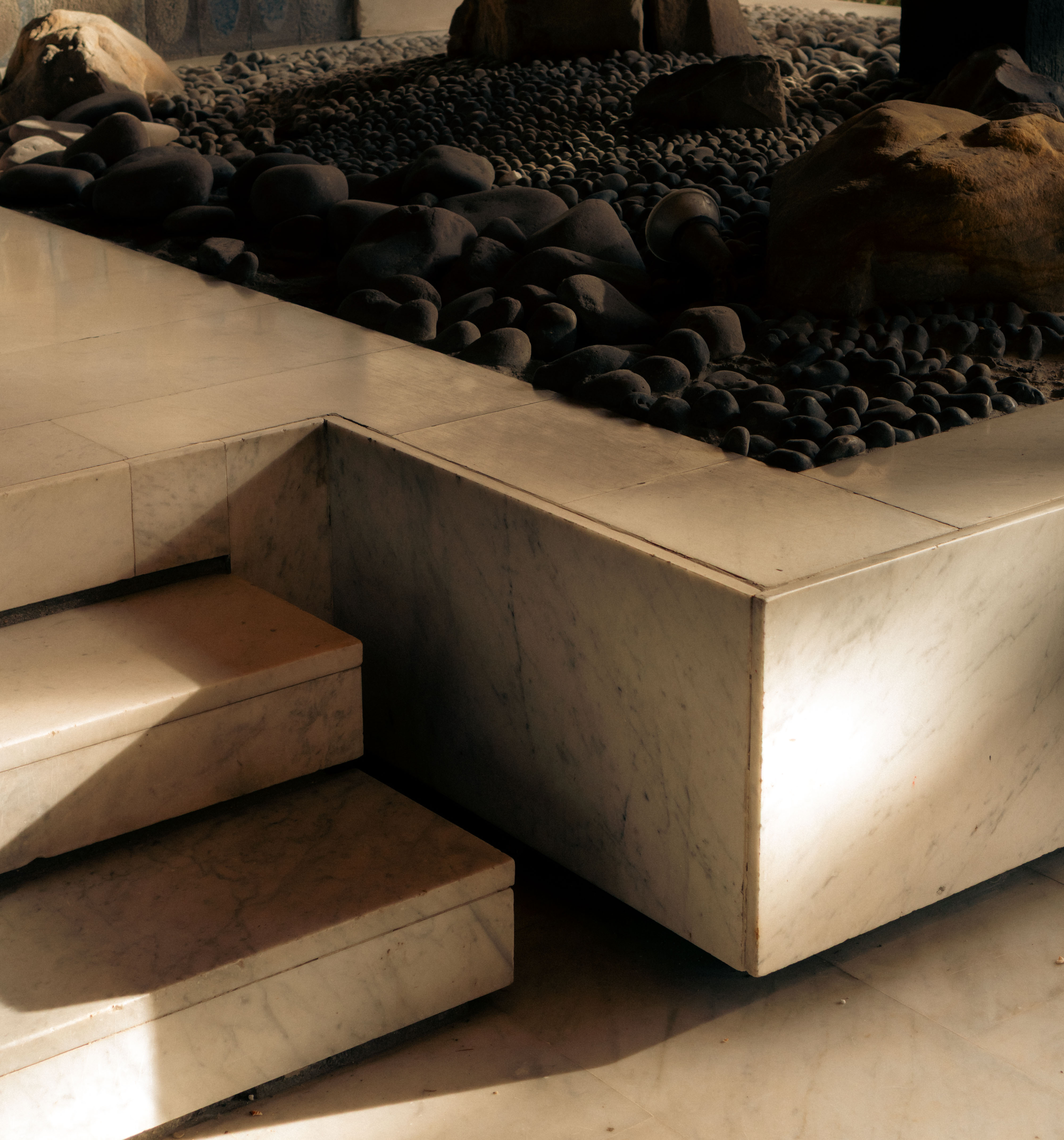 Bassin intérieur marbre blanc veiné, escalier monolithique, galets noirs