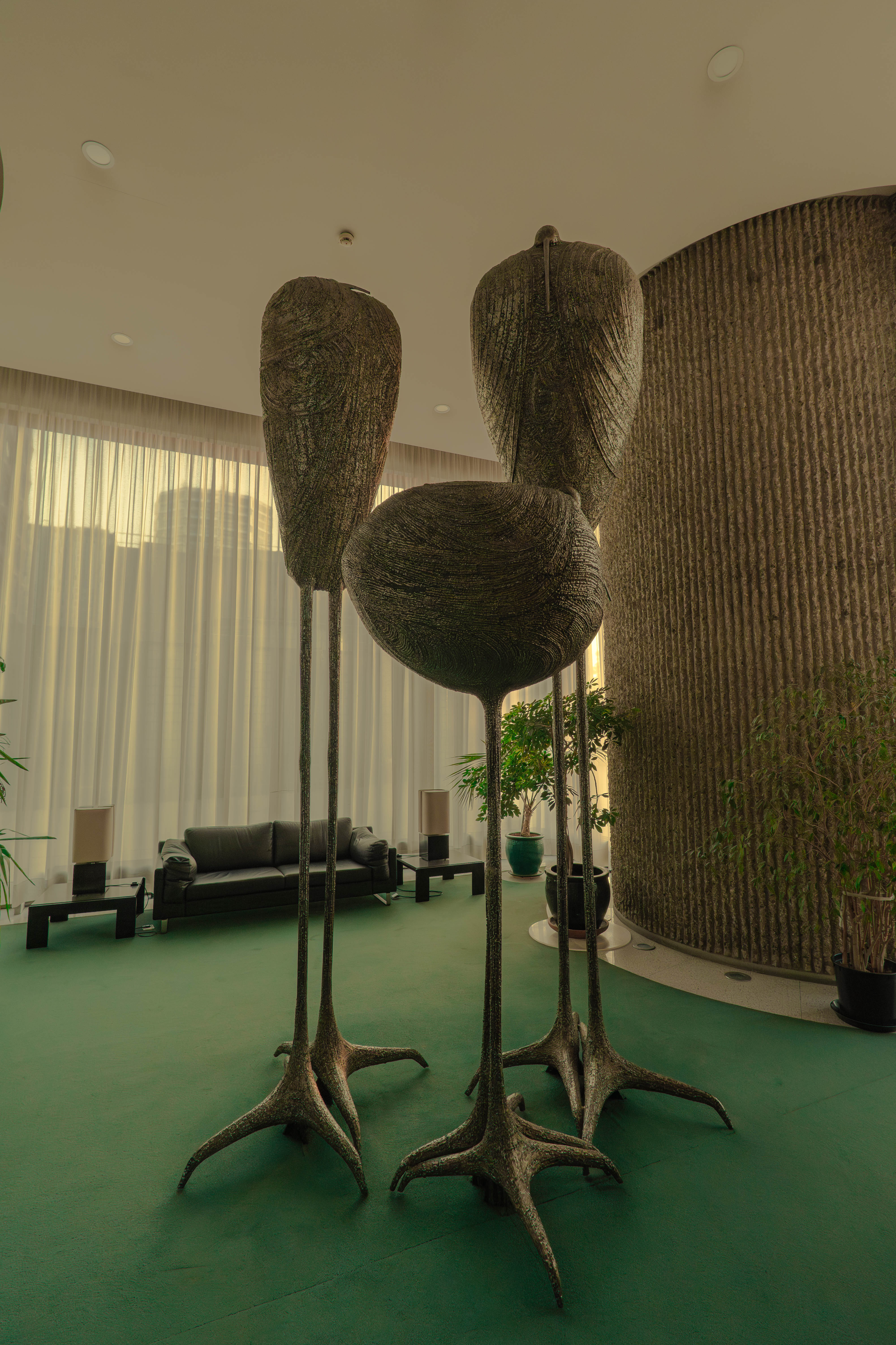 Trois sculptures zoomorphes bronze, hall vert, rideaux blancs