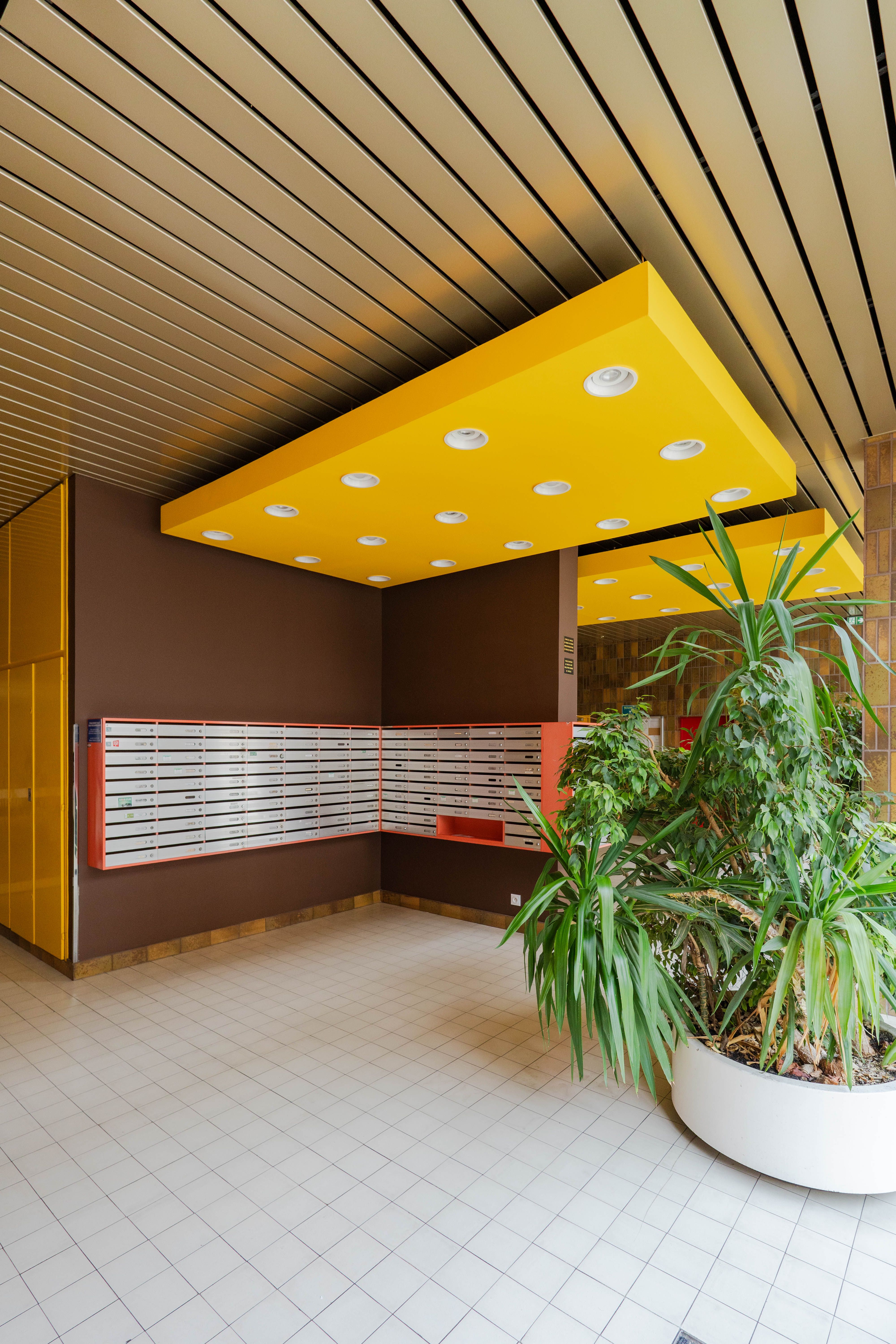 Hall d'immeuble parisien — béton, lumière rasante