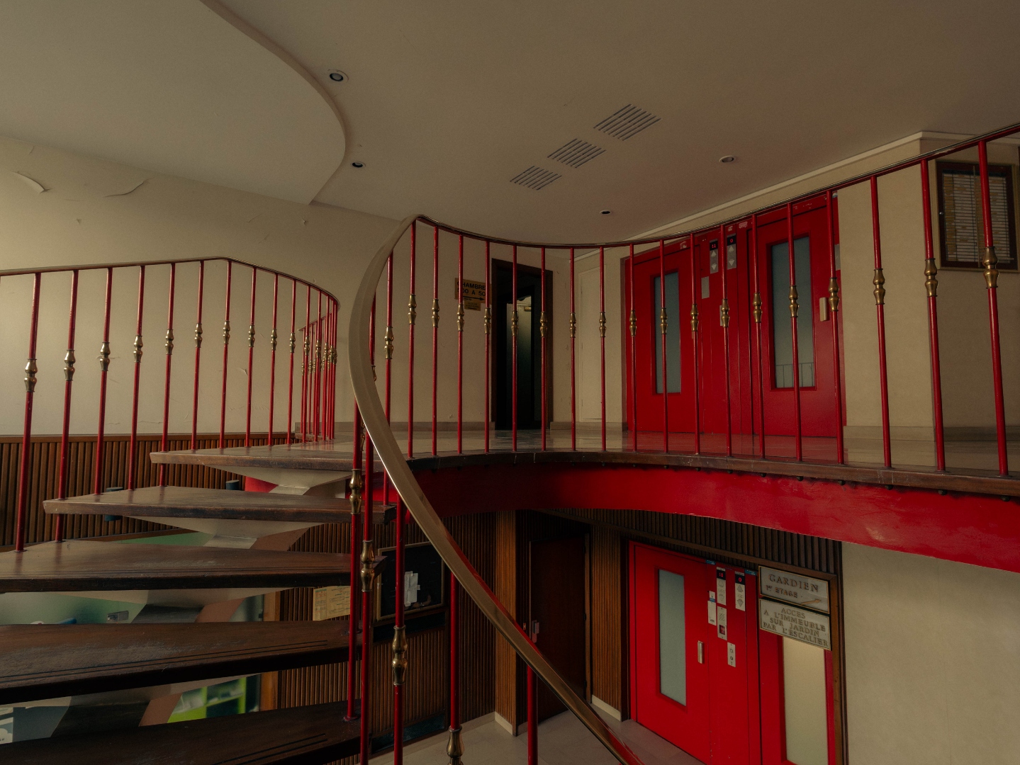 Hall — escalier spiral, mezzanine, rampe rouge