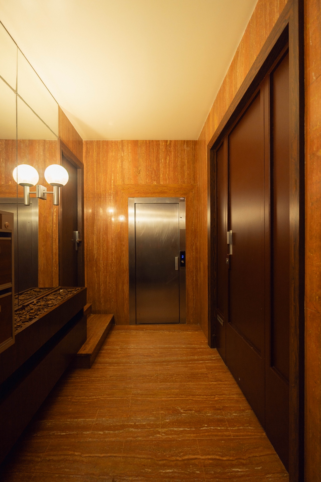 Hall — travertin rouge, ascenseur inox, miroirs